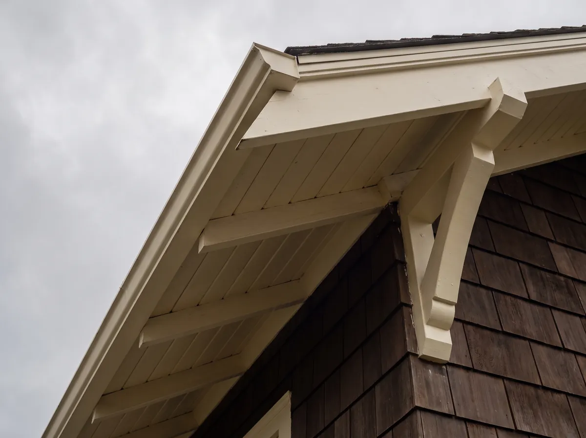 Painted cream eaves and knee braces on a Craftsman home with shingle siding